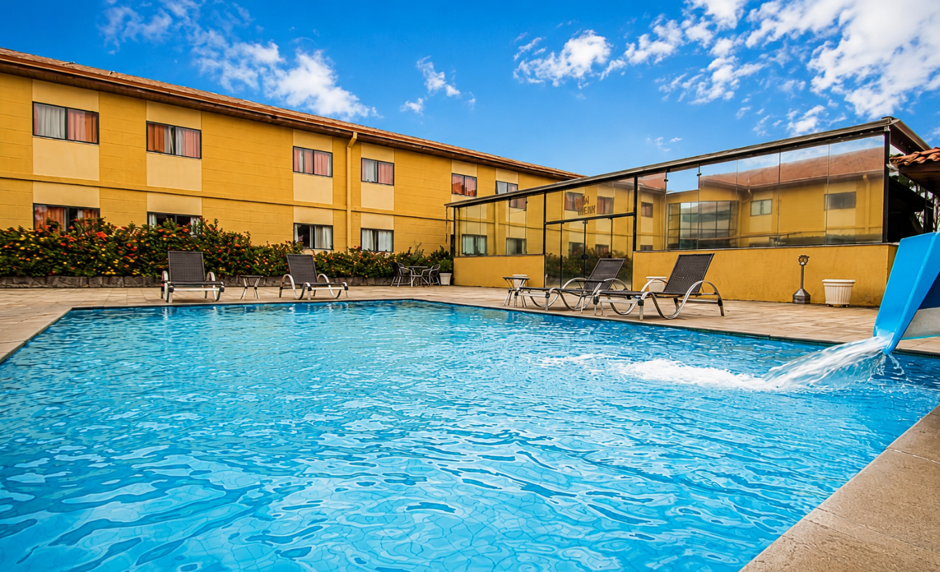 Piscina de hotel com espreguiçadeiras e área de lazer ao ar livre, ideal para famílias e viajantes corporativos